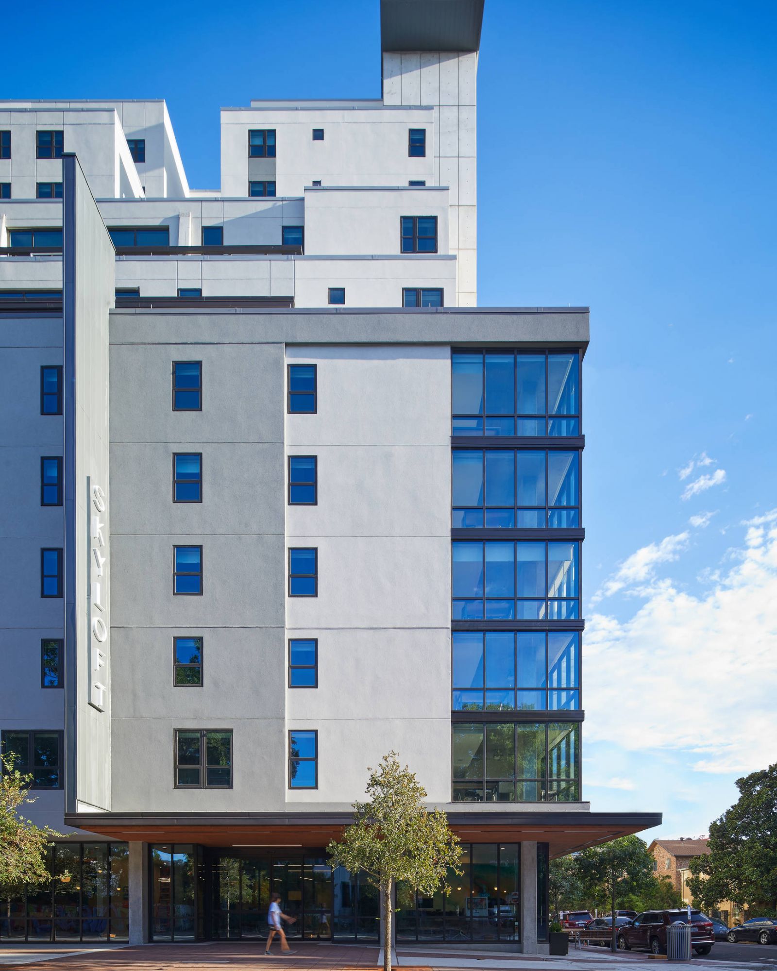 Modern multi-story hotel building with large blue-tinted windows and a sign reading "Aloft" on the facade.